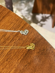 Close-up of gold and silver heart-shaped pendants with delicate chains on wood