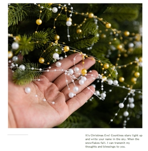Detail of hand holding gold and white pearl bead garland for Christmas tree decoration