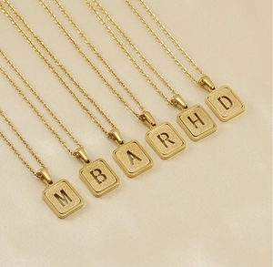 Detalle de seis collares con colgantes rectangulares dorados sobre tela de seda beige