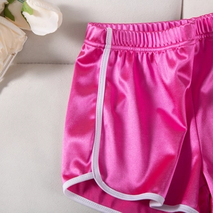 Detail of hot pink satin yoga shorts with white trim and elastic waistband