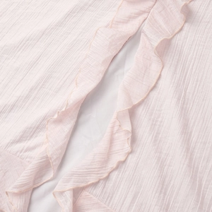 Detailed macro view of pink crinkled chiffon fabric with elegant ruffled edges on dress