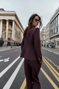 Détail d'un tailleur pantalon bordeaux avec veste ajustée dans un décor urbain chic