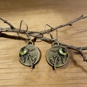 Detalle de pendientes vintage de girasol con gema verde oliva y acabado bronce antiguo