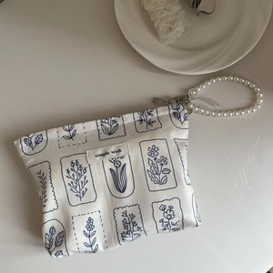 Detail shot of the floral cotton pouch featuring a large pearl beaded wrist strap
