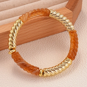 Gros plan détaillé des segments en métal doré et résine ambre sur un bracelet élastique