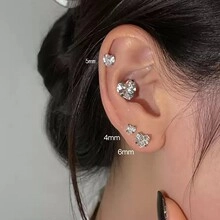 Model wearing silver heart cubic zirconia stud earrings in sizes 4mm, 5mm and 6mm
