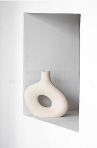 Close-up of minimalist pebble-shaped ceramic vase with hollow design and stone texture