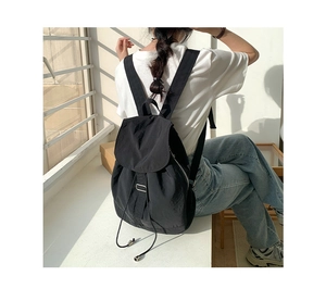 Zaino minimalista in nylon nero con chiusura a coulisse in un contesto di stile