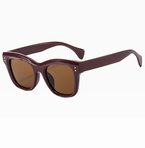 Detail view of burgundy cat-eye sunglasses with brown UV lenses and silver rivets