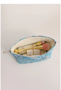 Spacious blue embossed floral makeup bag showing brushes, lotions, and lipstick storage