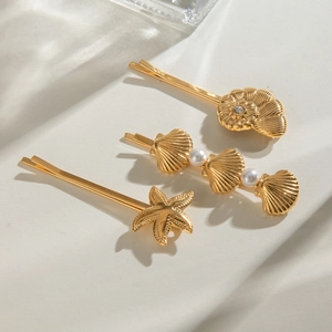 Close-up of 18k gold ocean-themed hair clips with pearls, shells and starfish charms