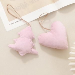 Addobbi natalizi in peluche rosa a forma di cuore e albero con corda di canapa su fondo beige