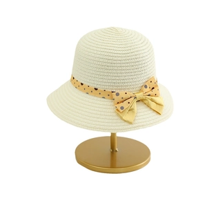 Kids straw sun hat with yellow polka dot ribbon and bow on golden metal stand