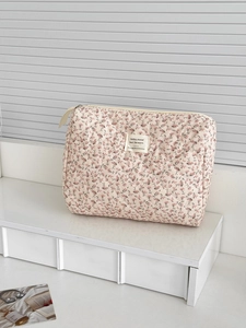 Quilted floral corduroy makeup bag with pink flower pattern on a white display stand