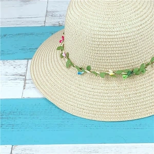 Close-up of summer straw hat with floral wreath decoration and fine woven texture