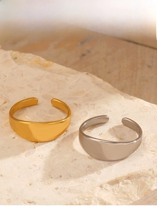 Polished gold and silver thick open rings on a textured beige stone background