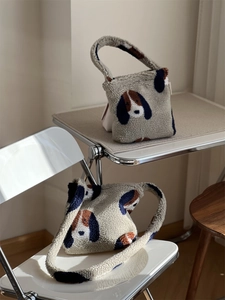 Détail de sacs en laine d'agneau pelucheux avec motifs de chiens sur chaise blanche