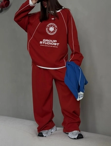 Detail of red athletic set featuring side stripe accents and white logo on sweatshirt