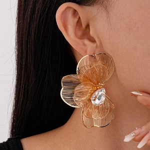 Close-up of a large gold woven floral earring with a crystal center on model