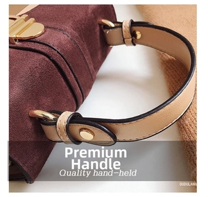 Detail of burgundy frosted suede handbag with golden metal hardware and beige knit background