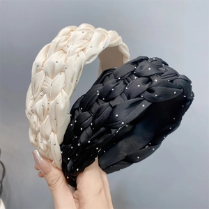 Detail of hand holding beige and black braided headbands with sparkling rhinestones
