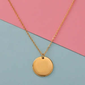 Detailed close-up of a polished gold minimalist round pendant on a fine link chain necklace