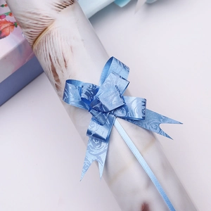 Close-up of blue gift pull bow with elegant rose pattern for festive gift wrapping