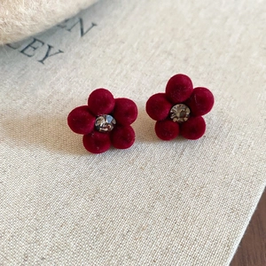Détail de boucles d'oreilles fleurs en velours rouge avec cristal sur papier vintage