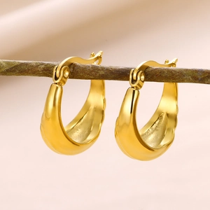 Detailed view of chunky gold geometric U-shaped hoop earrings on a natural branch