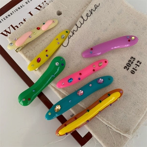 Colorful acrylic duckbill hair clips with rhinestones set on a beige canvas bag