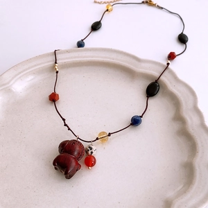 Close-up of vintage multi-color beaded necklace with a carved wooden pony pendant in a ceramic dish