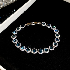 Gros plan d'un bracelet pendentif circulaire en zircon bleu sur écrin velours