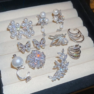 Close-up of silver zircon and pearl jewelry collection including ear cuffs and rings