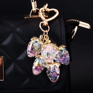 Detailed shot of rainbow crystal strawberry charm with rhinestones on a black handbag