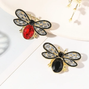 Macro detail of bee brooches with red and black gemstones and baguette crystals