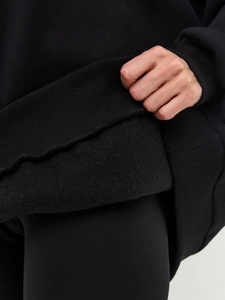 Close-up of black sweatshirt showing thick fleece lining and ribbed knit cuff texture