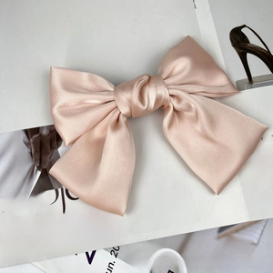 Close-up of a large champagne pink satin bow hair clip with premium silk texture