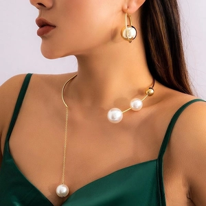 Detail of gold choker necklace with white faux pearls and tassel drops on model