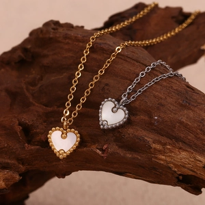 Vue macro des colliers cœur en or 18 carats et argent avec nacre blanche sur bois