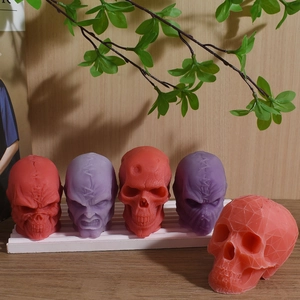 Detailed skull candles in red and purple styles on wood and white trays for decor