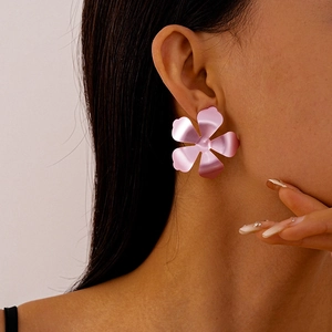 Close-up of oversized metallic pink flower earrings with a matte textured finish