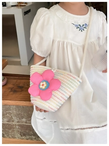 Detailansicht der gewebten Strohtasche mit bunten Wellenlinien und rosa 3D-Blumenapplikation