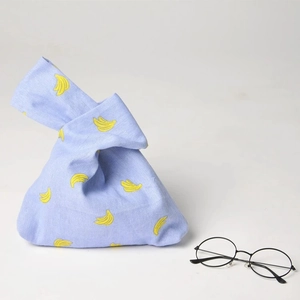 Japanese knot wrist bag in light blue cotton with yellow banana pattern embroidery