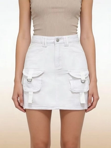 Detail of white high-waisted denim skirt featuring large flap pockets and metal D-rings