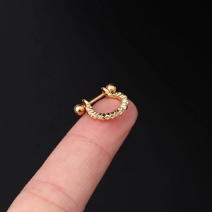 Macro shot of 20G gold horseshoe stud with cubic zirconia inlays on a fingertip