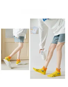 Close-up of yellow cotton socks with cute cartoon eyes and contrast orange cuffs