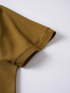 Detailed close-up of ribbed cuffs and mustard yellow pique knit fabric on men's polo shirt