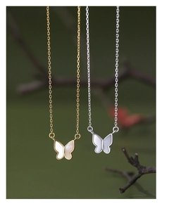 Detail of silver and gold butterfly necklaces with white mother-of-pearl inlay pendants