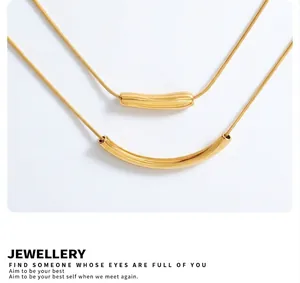 Détail de colliers chaîne serpent dorée à plusieurs rangs avec pendentifs tubes courbés