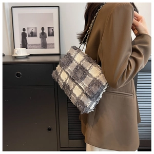 Detail view of a plaid tweed shoulder bag with metal chain strap and fringe trim edges